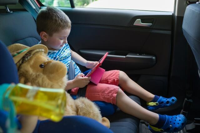 車内でタブレットを見る子供