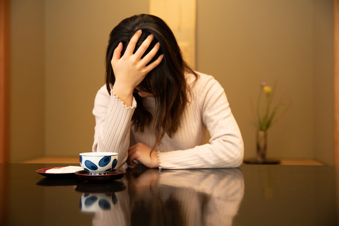 旅館の部屋で頭が痛そうな女性