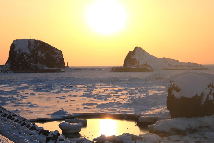 流氷の上を歩く「流氷ウォーク」で大自然を体感できるほか、海を覆う氷原の向こうに夕日が沈む光景
