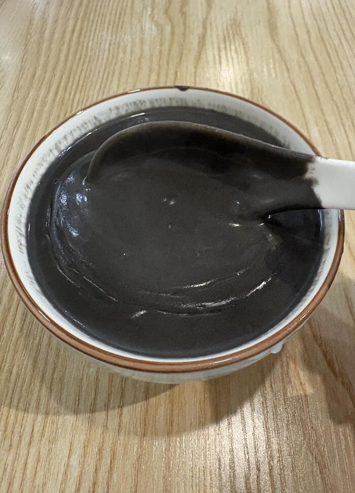 黒い芝麻糊をスプーンですくっている様子
