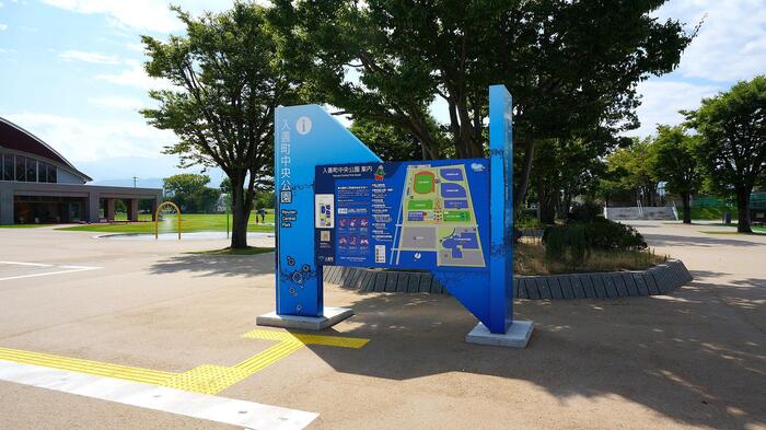 入善町中央公園の芝生広場が見える公園入口、青い案内板と看板