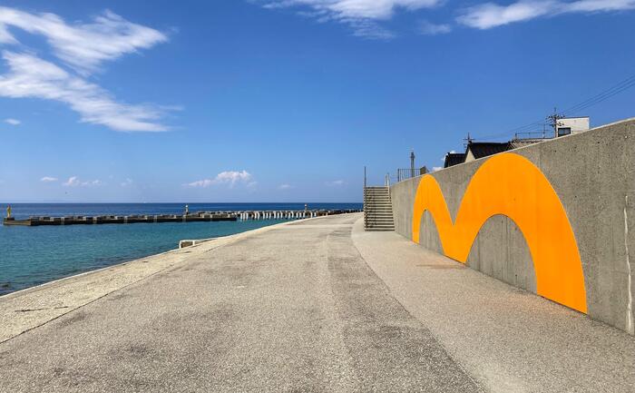生地海岸に設置された巨大な「m」型看板《infinity～mirage》と富山湾の景色