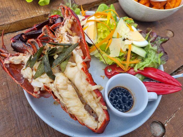 半身の焼いたザリガニにセージとサラダがのるプレート
