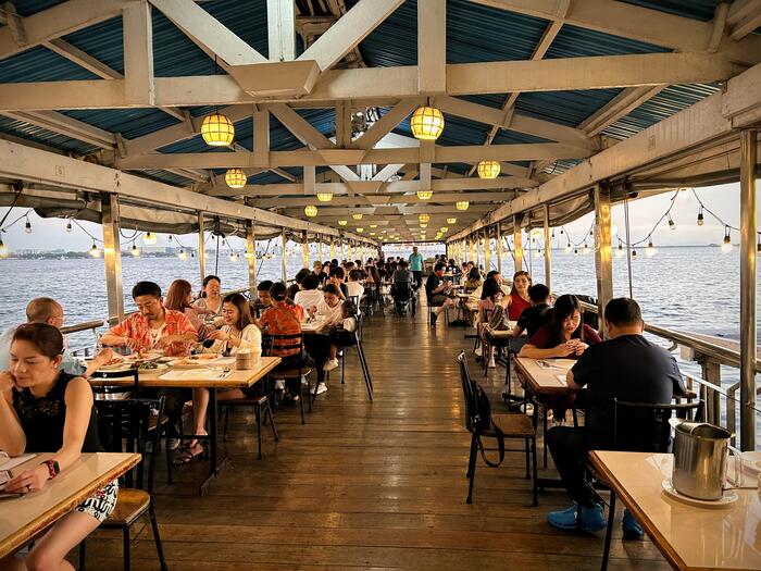 海沿いのおしゃれなシーフードレストランでテーブルに座って食べる人々