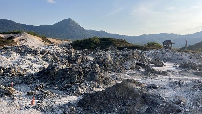 硫黄の香りが漂う恐山の岩場と風車が回る静かな風景