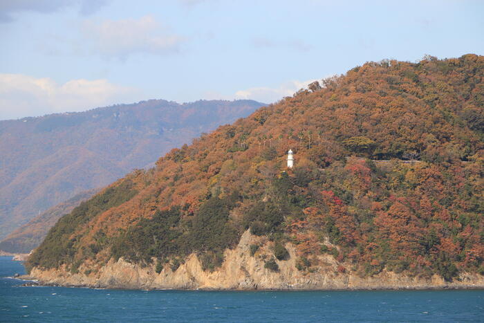 船上から紅葉に色づく小豆島と大角鼻灯台を眺める