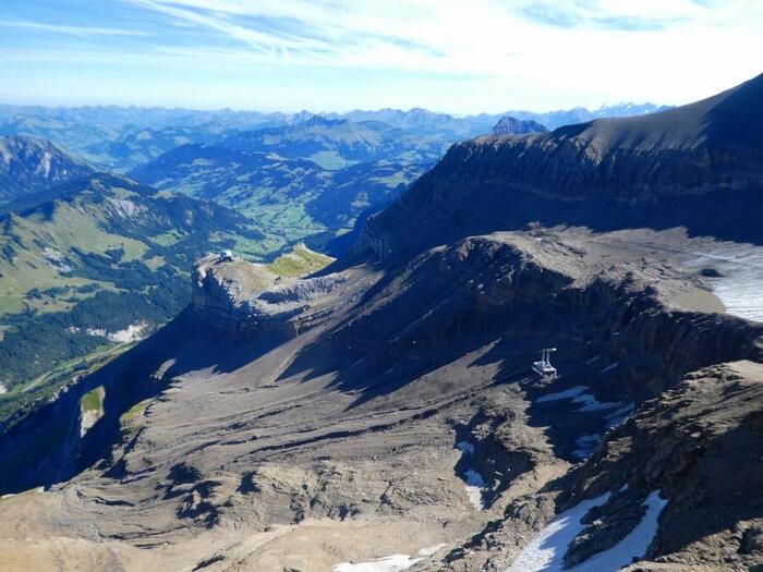 山頂から見下ろすスイスの大自然と小さく見えるロープウェイゴンドラ