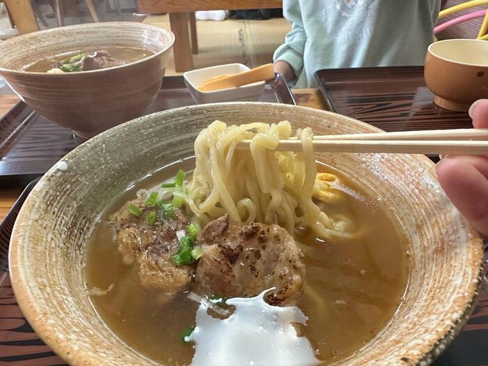 介そば 軟骨ソーキそばの太麺を箸であげる様子